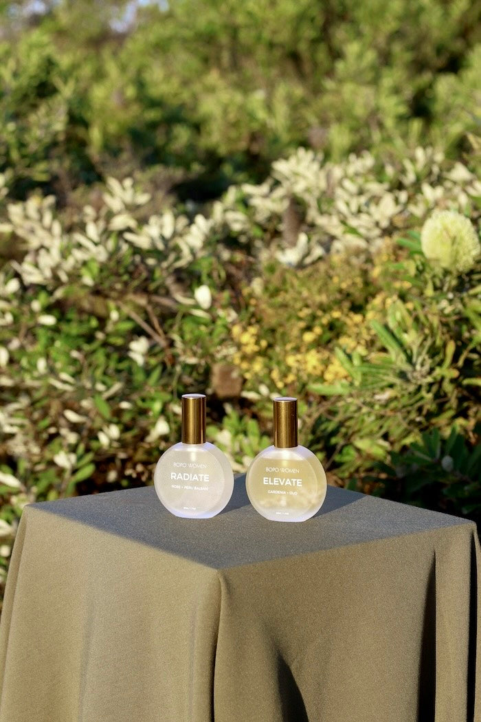 Two perfume bottles on a table with a natural background