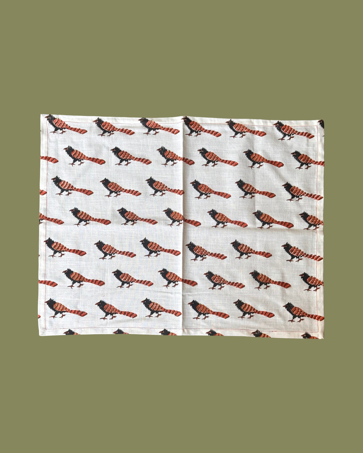 A rectangle white cotton teatowel featuring a repeating pattern of pheasant coucal birds with orange and red striped tails, laid flat against a solid olive green background.
