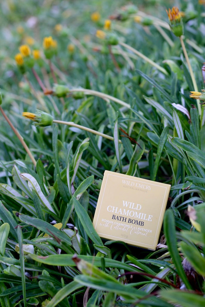 Yellow wild emery wild chamomile  bath bomb packaging in a grassy field with wildflowers