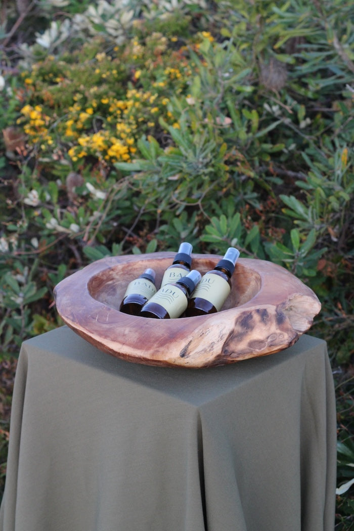 Badu Natural Aromatherapy Mists in a wooden bowl in the Australian bush