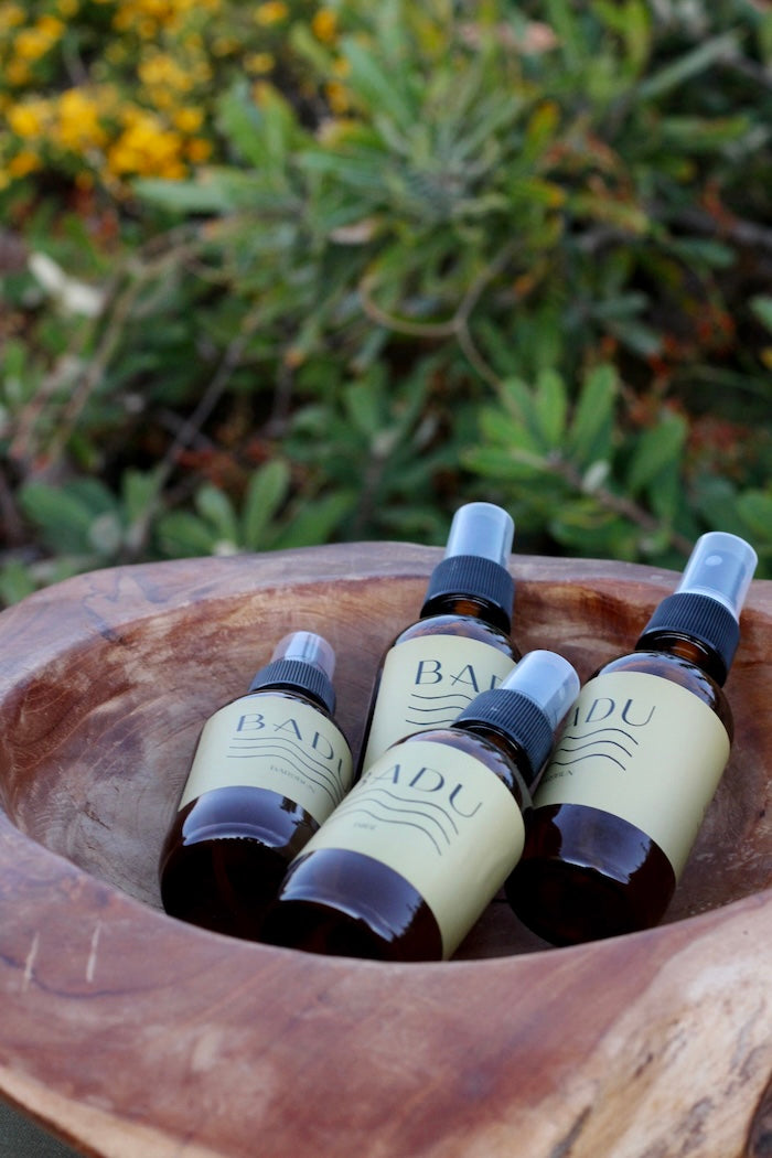 Four bottles of Badu in a wooden bowl with a natural background