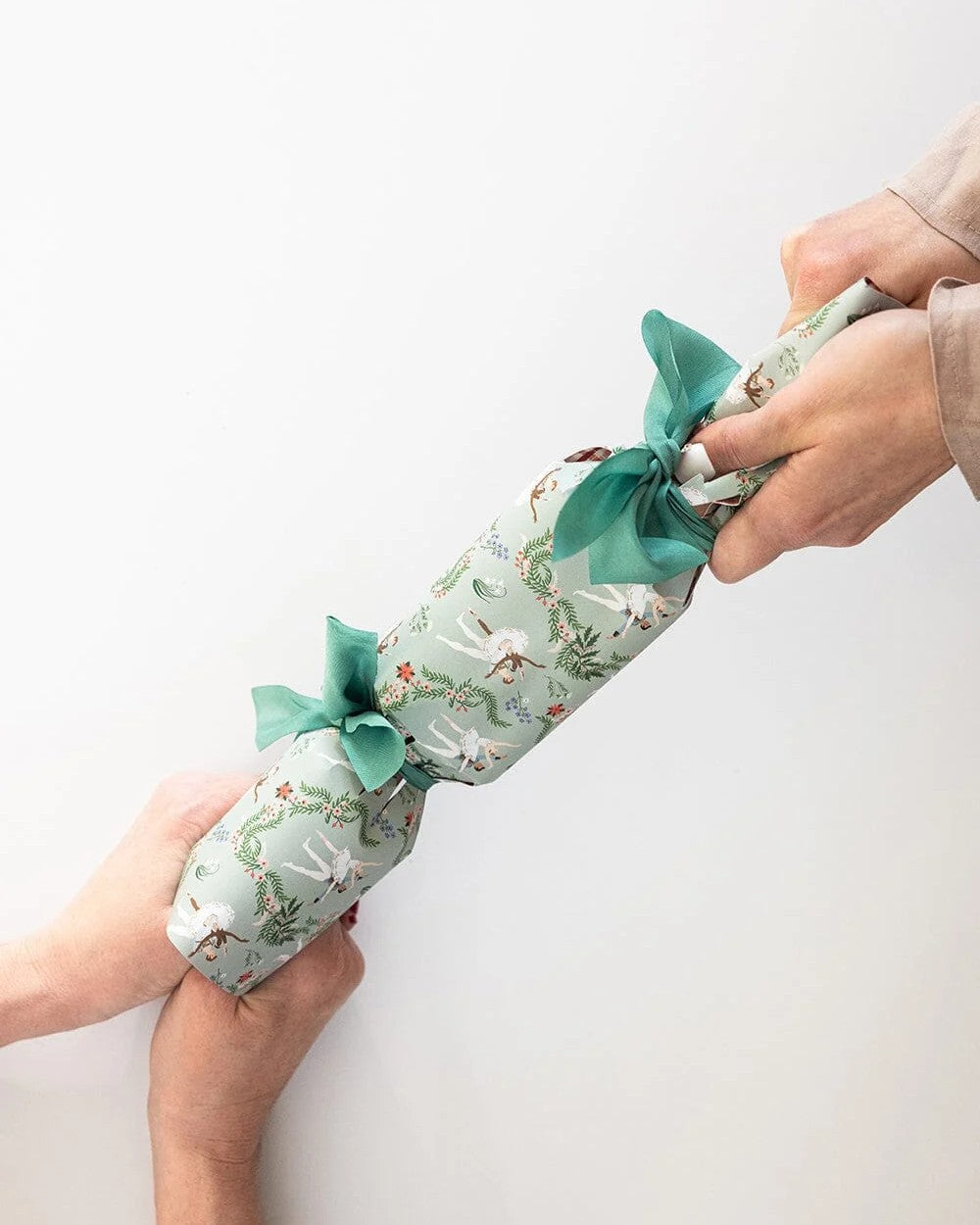 Two people pulling an Enchanted green floral Christmas cracker