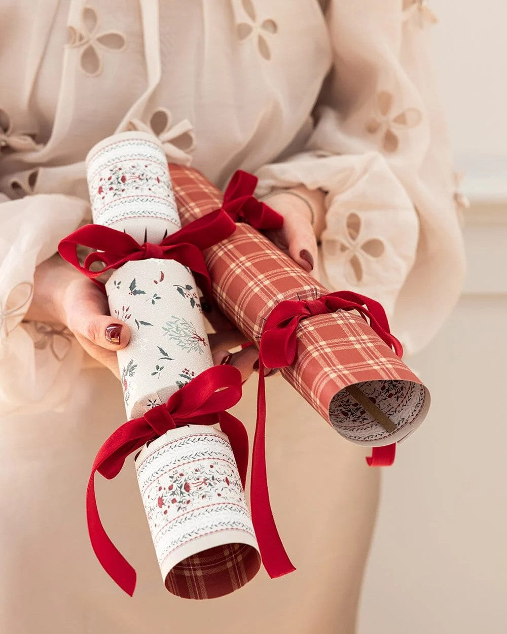 Two finished Heirloom Holly Christmas crackers held with red velvet bows