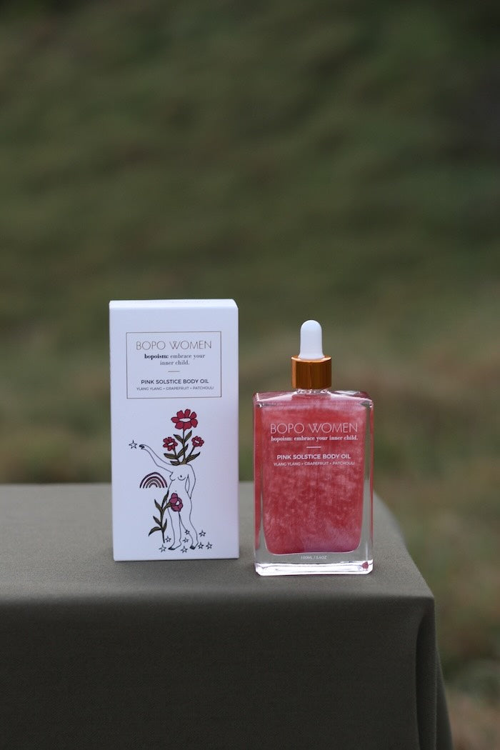 Bottle and packaging of Bopo Women Pink Solstice Body oil with green background 