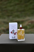 Bottle and box of Bopo Women Summer Solstice on a gray surface with a blurred green background