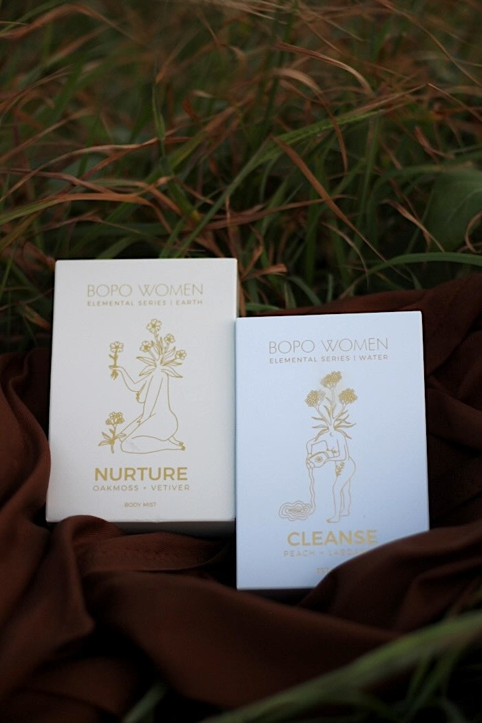 Two boxes labeled 'Nurture' and 'Cleanse' by Bopo Women on a brown fabric background with grass. Black Head Ballina