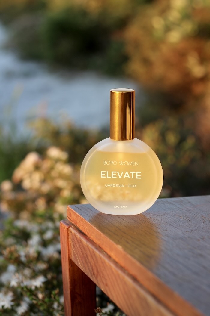 Bottle of 'Elevate' perfume by bopo women on a wooden surface with a blurred natural background at Lennox Head