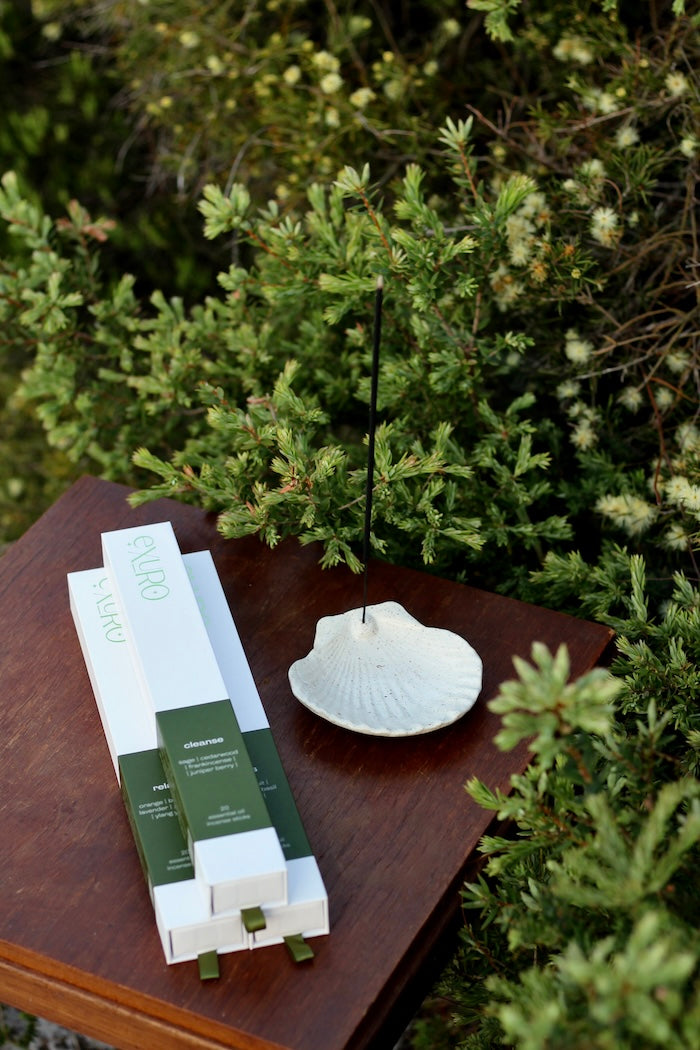 Exuro aromatherapy cleanse incense box sitting on table with Collective Autonomy handmade shell incense holder 