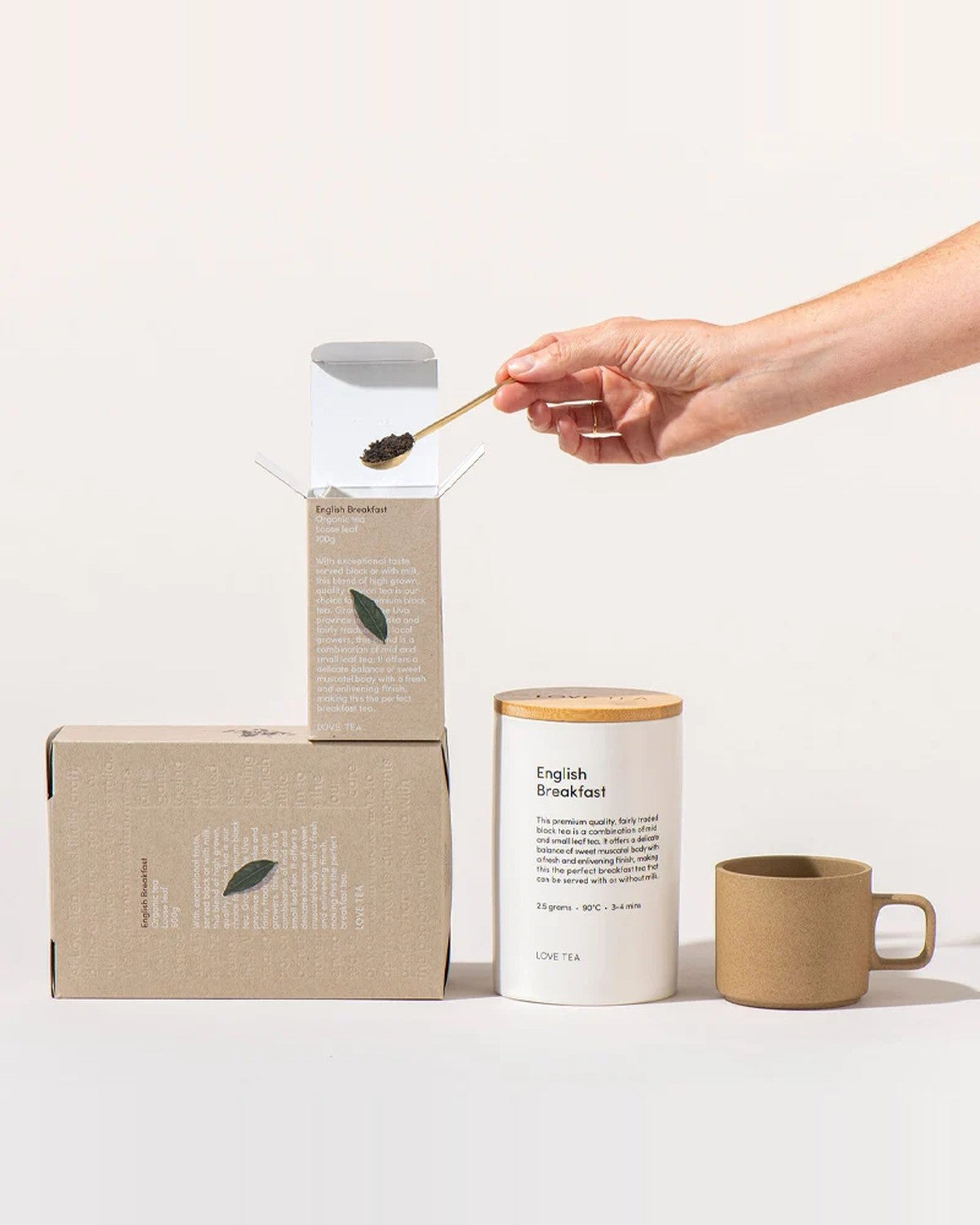 Love Tea English Breakfast tea box, canister and mug with a hand scooping loose leaf tea
